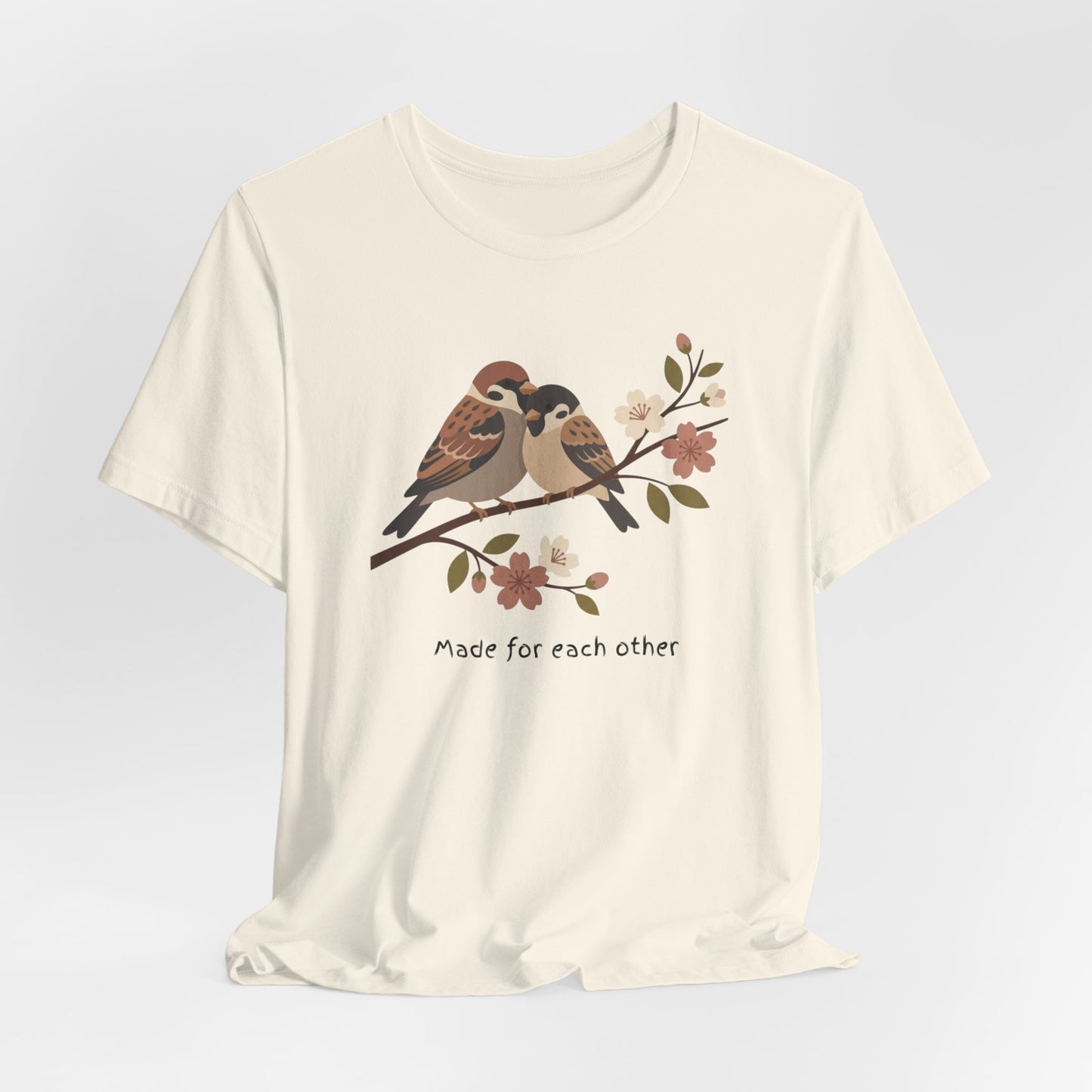 Cream t-shirt with a graphic of two birds on a branch and the text 'Made for each other' on a light gray background.